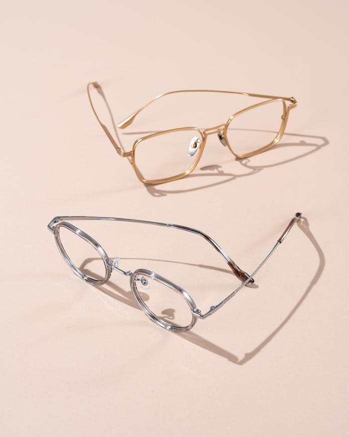 Pair of stylish eyeglasses on a beige surface in minimalist setup