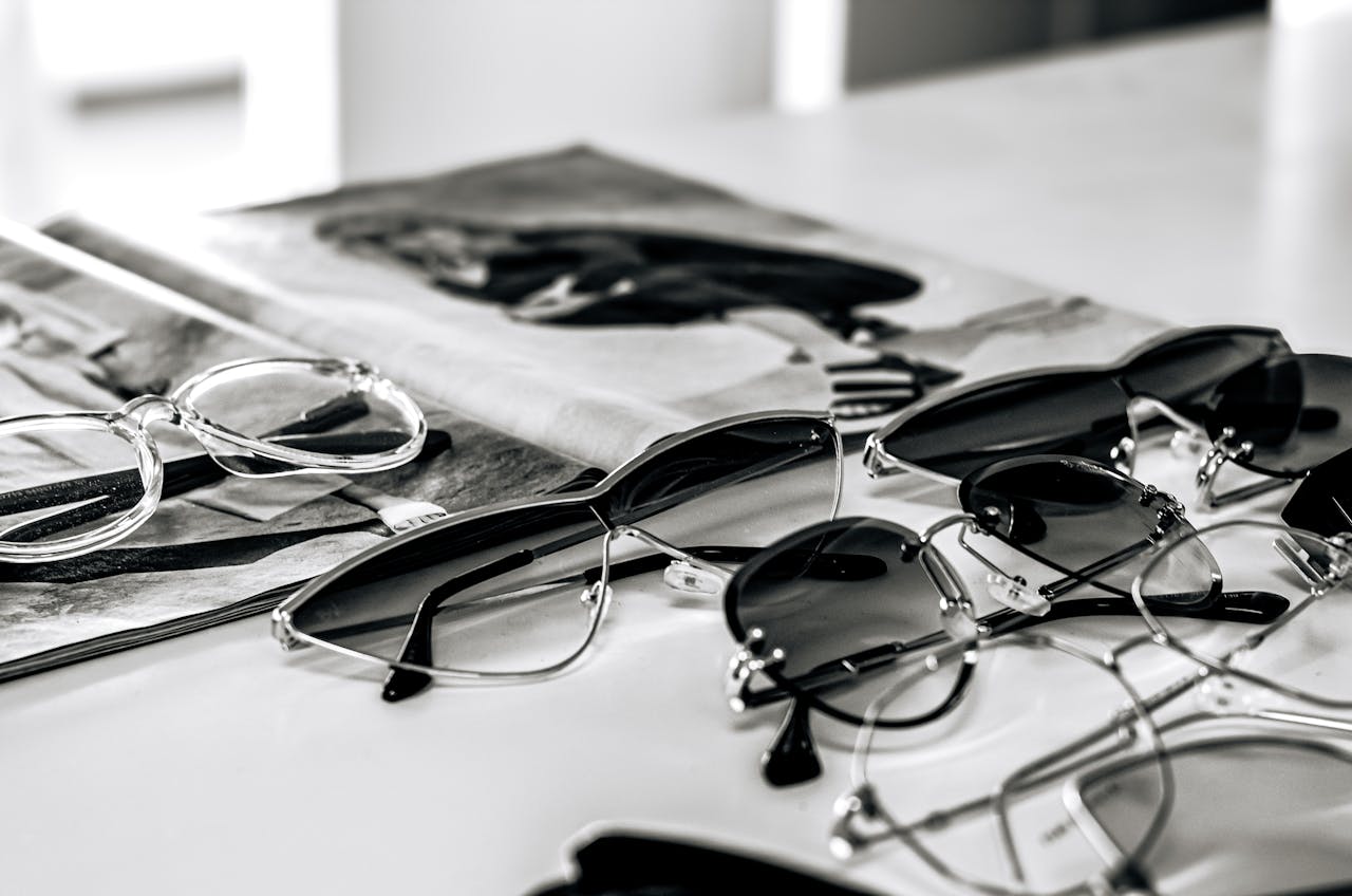 Stylish sunglasses arranged on a glossy magazine in a sleek black and white composition.
